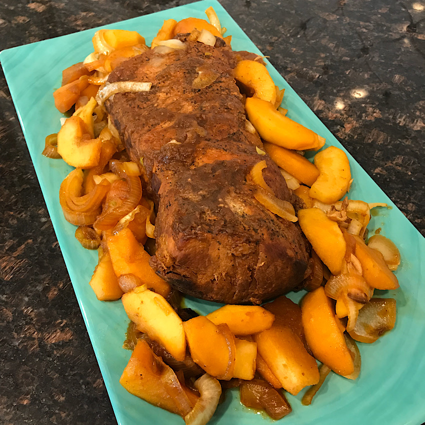 Slow Cooker Apple Butter Pork Loin ready to serve. Surrounded with apples and onions. So delicious!