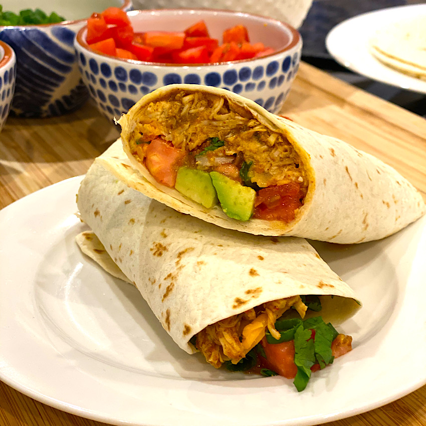 No Chop Crockpot Mexican Chicken used in a burrito. Here it was topped with lots of fresh veggies and shredded cheese.