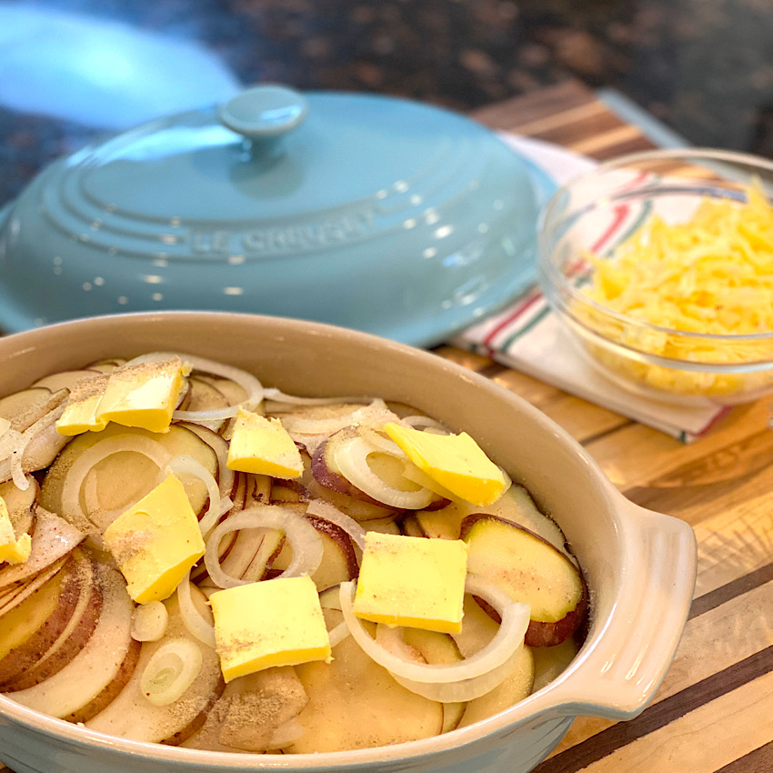 Photo shows layers of potatoes, onion, and butter pats