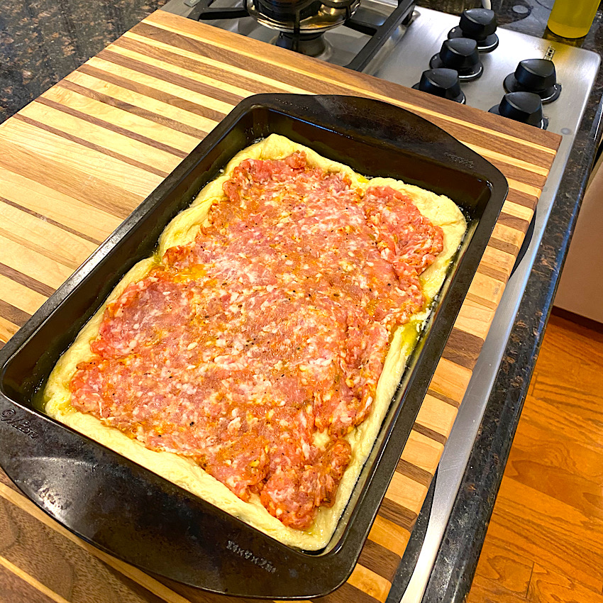 Cake Pan Deep Dish Pizza being assembled. Picture shows italian sausage layer.