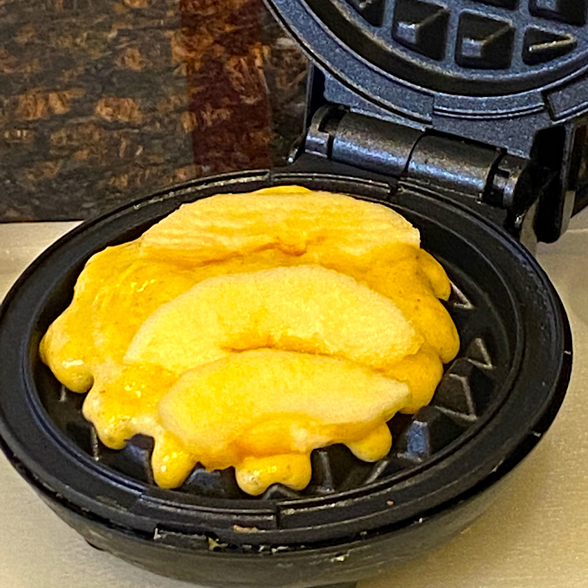 Waffle mix and fresh apples in the waffle maker